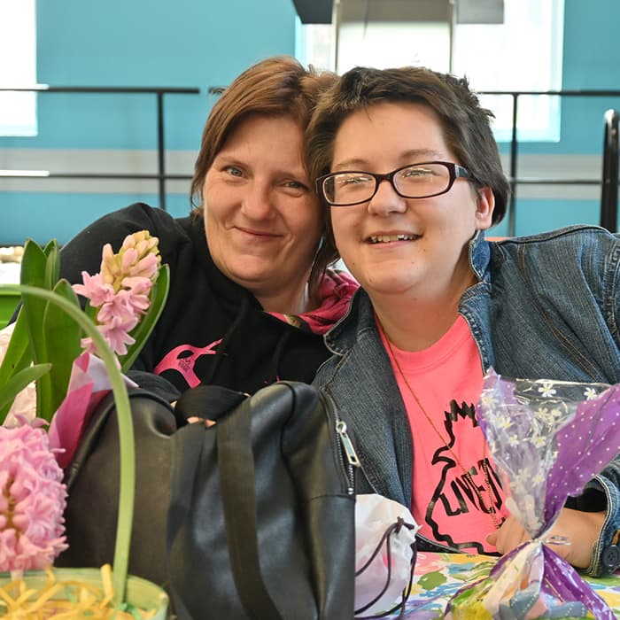 Two female members sit next to each other with smiles on their face as they engage in a mental health recovery activity